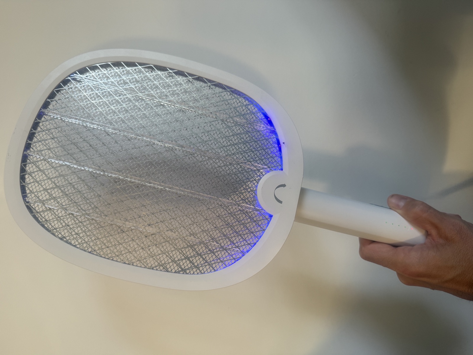 La raquette &eacute;lectrique YISSVIC 4000V tenue en main, grille d&eacute;pli&eacute;e et LED violettes allum&eacute;es le long du bord bas, en mode manuel
